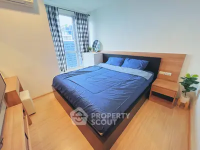 Modern bedroom with blue bedding and city view, featuring wooden furniture and stylish decor.