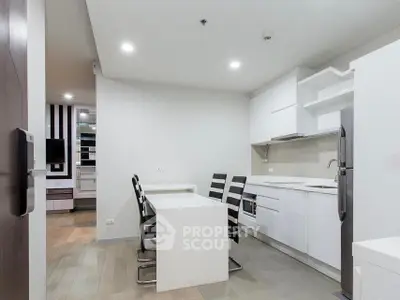 Modern kitchen with sleek white cabinets and dining area in contemporary apartment