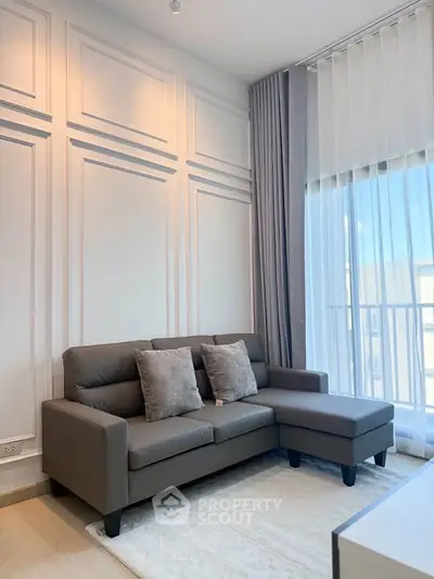 Modern living room with stylish gray sofa and large window offering natural light.