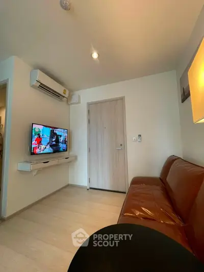 Modern living room with leather sofa and wall-mounted TV in cozy apartment.