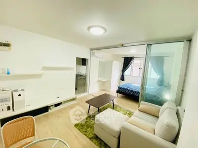 Modern open-plan living room with cozy seating and bedroom view in stylish apartment.