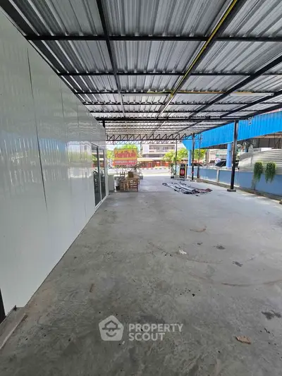 Spacious covered outdoor area with metal roofing and concrete flooring, ideal for versatile use.