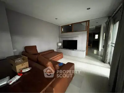 Modern living room with brown leather sofa and wall-mounted TV in a cozy apartment.