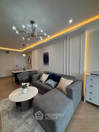 Modern living room with elegant decor, featuring a stylish chandelier and cozy seating area.