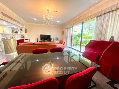 Spacious living room with elegant chandelier and garden view, featuring modern furniture and open layout.