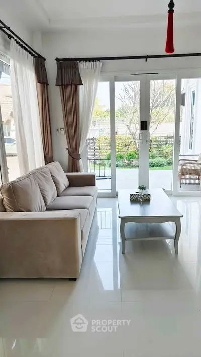 Bright living room with large windows and cozy sofa, offering a serene garden view.