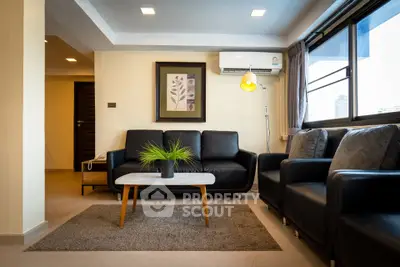 Modern living room with stylish black leather sofas and a cozy ambiance.
