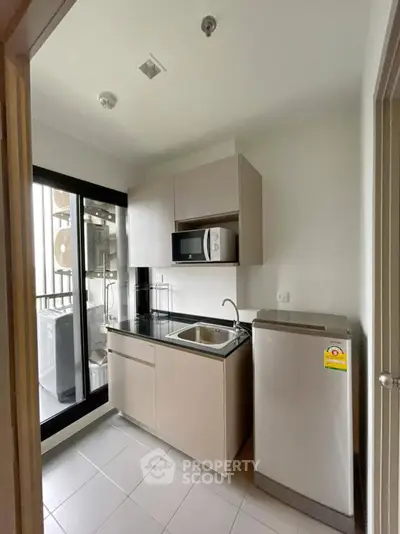 Modern compact kitchen with sleek cabinetry and appliances in a bright apartment.