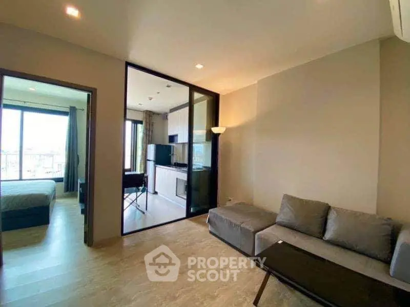 Modern living room with open layout and cozy furniture, adjacent to a bedroom with large windows.