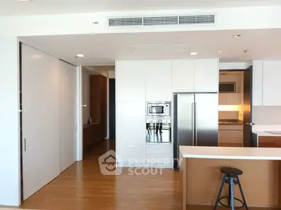 Modern kitchen with sleek appliances and wooden flooring in a stylish apartment.