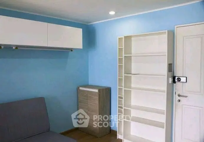 Modern minimalist room with blue walls, white shelving, and sleek furniture.