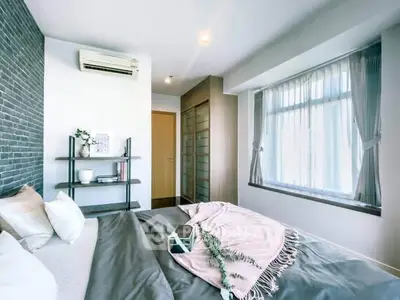 Modern bedroom with large window, stylish decor, and cozy bedding in a bright apartment.