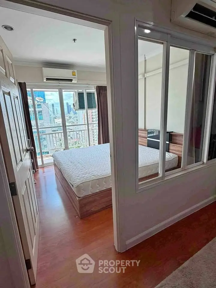 Spacious bedroom with city view and modern decor in high-rise apartment.