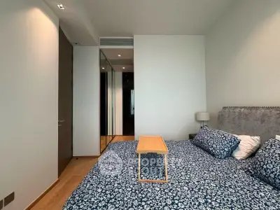 Modern bedroom with stylish decor and mirrored closet doors in a luxury apartment.