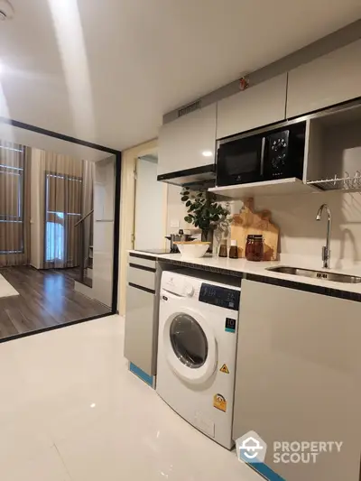 Modern kitchen with washing machine and sleek cabinetry in stylish apartment