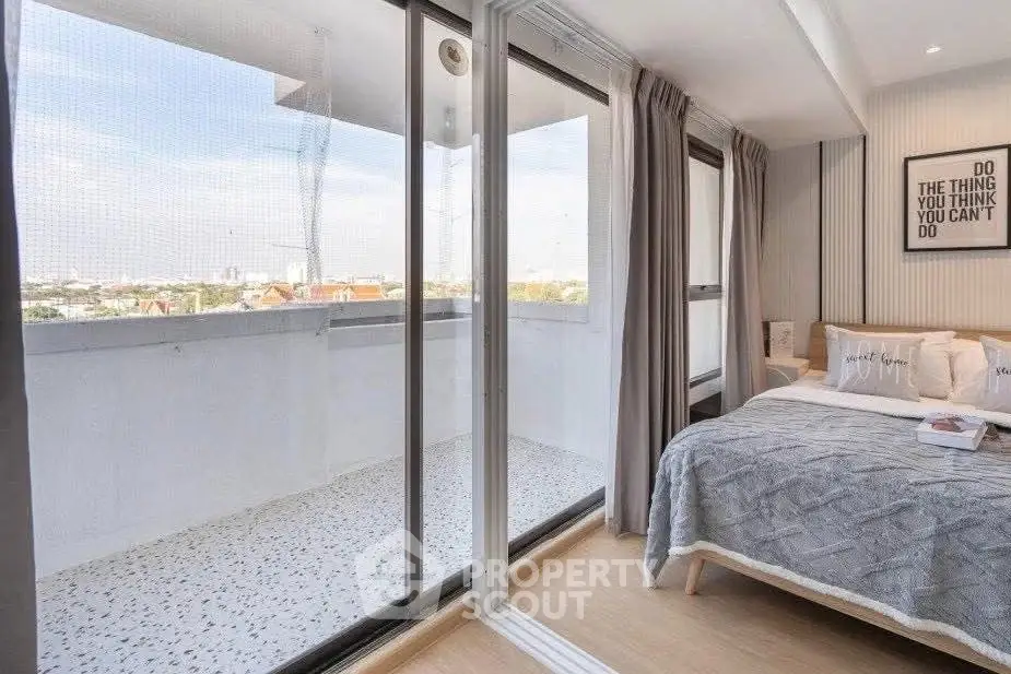 Modern bedroom with balcony access and city view, featuring stylish decor and ample natural light.