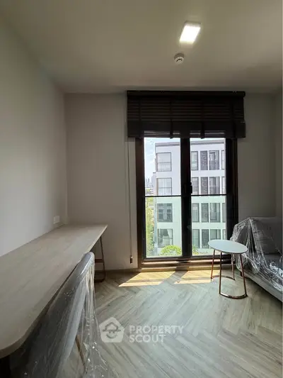 Modern apartment interior with large window and stylish furniture, offering a bright and inviting living space.