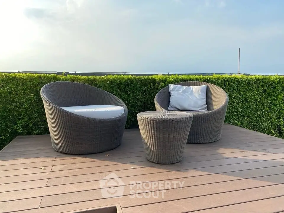 Chic outdoor patio with modern wicker chairs and lush greenery, perfect for relaxation and entertaining.
