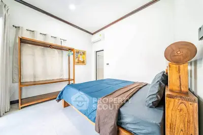 Spacious bedroom with modern decor and natural light, featuring a cozy bed and stylish wooden furniture.