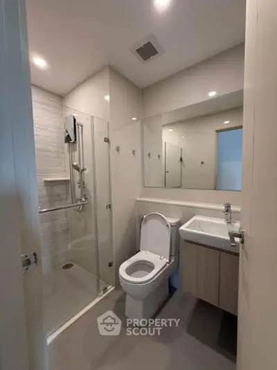 Modern bathroom with glass shower and sleek fixtures in contemporary apartment.