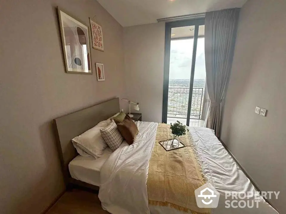 Cozy bedroom with modern decor and balcony offering stunning city views, perfect for urban living.