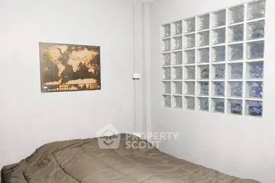 Cozy bedroom with modern decor and glass block wall feature.