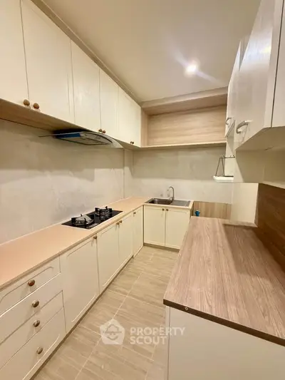 Modern kitchen with closed layout and gas stove, featuring sleek cabinetry and ample counter space.
