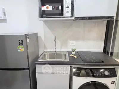 Modern kitchen with sleek appliances including fridge, microwave, and washing machine in compact layout.