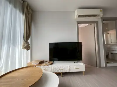 Modern living room with sleek TV setup and air conditioning, featuring stylish furniture and natural light.