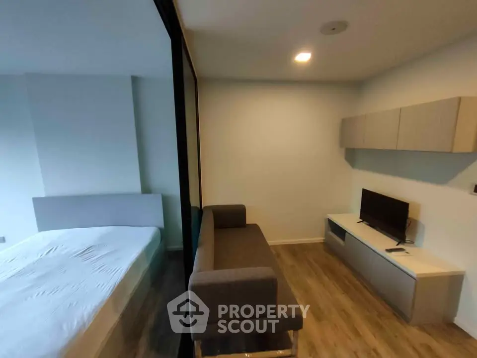Modern studio apartment with cozy living area and bedroom separated by glass partition.