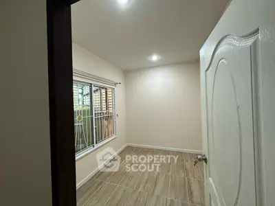 Spacious empty room with large window and elegant flooring, perfect for customization.