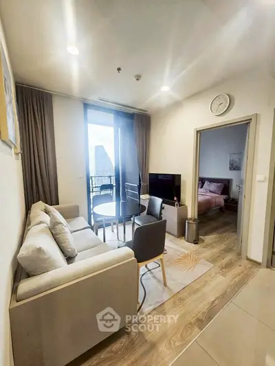 Modern living room with cozy sofa, TV, and balcony access, adjacent to a stylish bedroom.