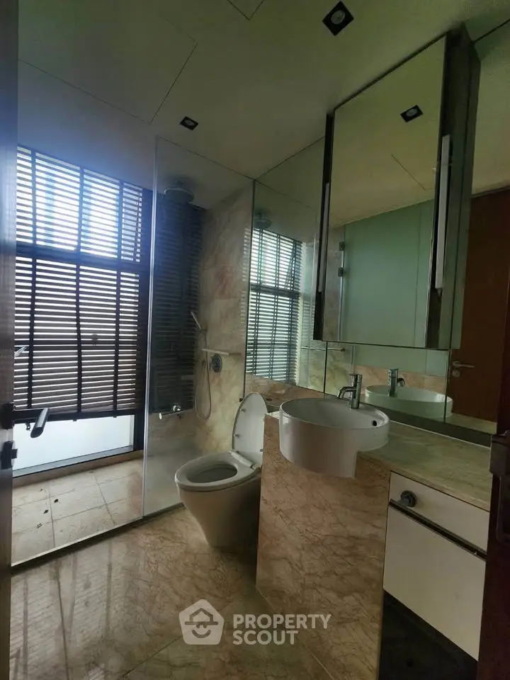 Luxurious bathroom with modern fixtures and marble accents, featuring a glass-enclosed shower and sleek vanity.