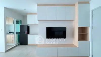 Modern kitchen and living area with sleek cabinetry and mounted TV, featuring a minimalist design.
