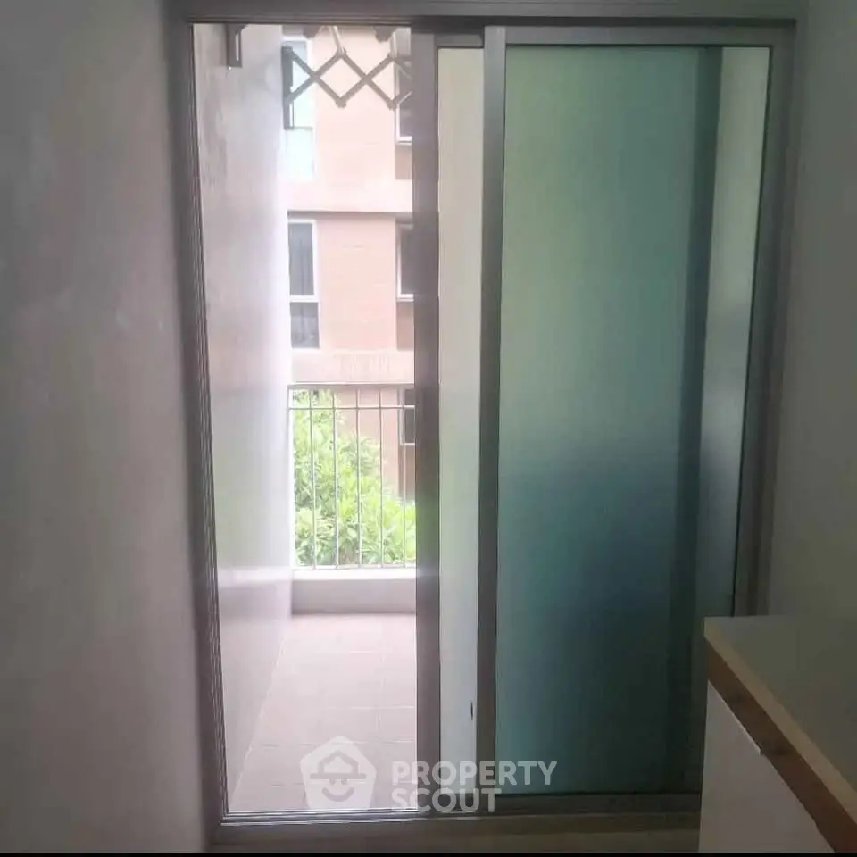 Modern apartment with sliding glass door leading to a small balcony with urban view.