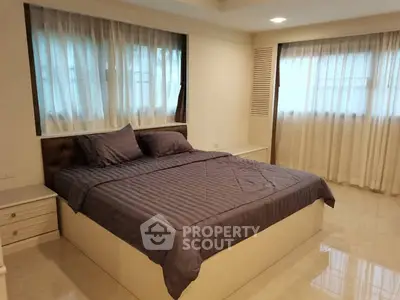 Spacious bedroom with elegant decor and large windows for natural light.