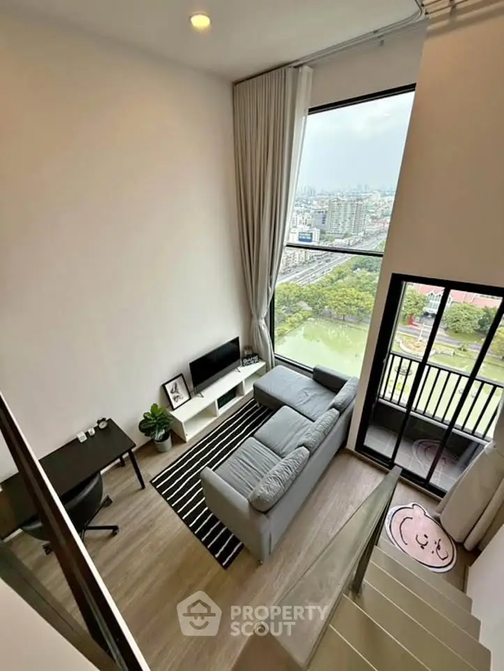 Modern loft apartment with high ceilings, large windows, and a stunning city view from the balcony.