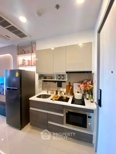 Modern kitchen with sleek cabinetry, built-in microwave, and stylish decor in a compact layout.