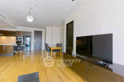 Modern open-plan living room with sleek kitchen and dining area, featuring hardwood floors and contemporary furniture.