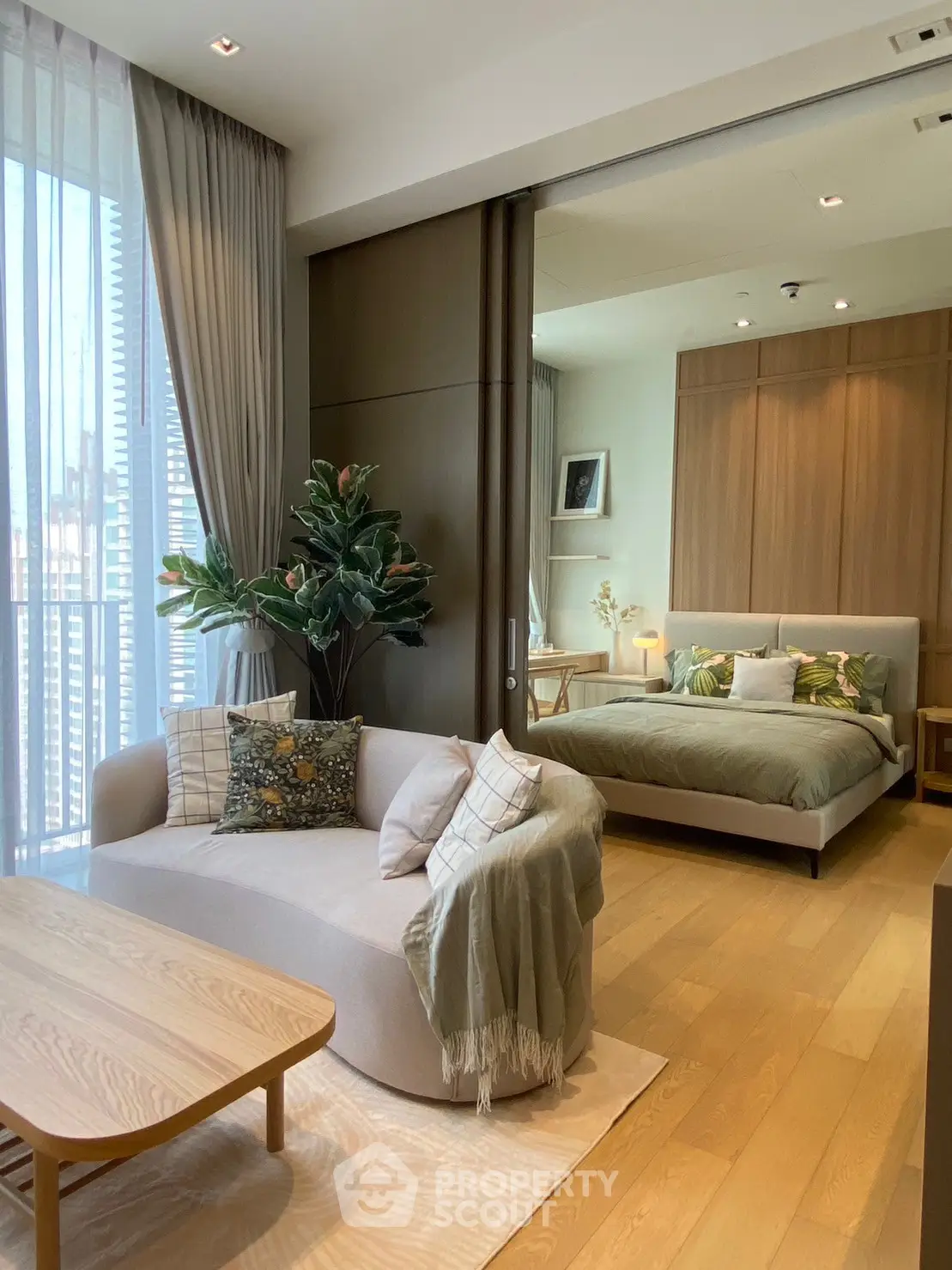 Stylish open-plan living room and bedroom with modern decor and large windows.