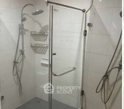 Modern bathroom with glass shower enclosure and dual shower heads.