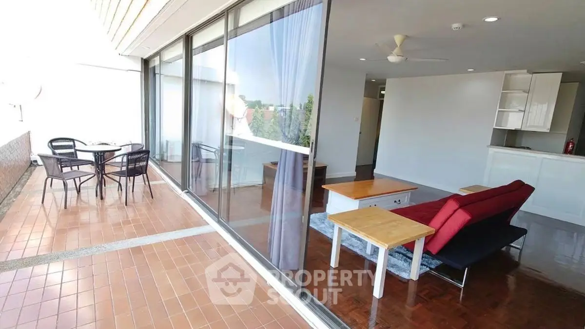 Spacious balcony with sliding glass doors opening to modern living room and dining area