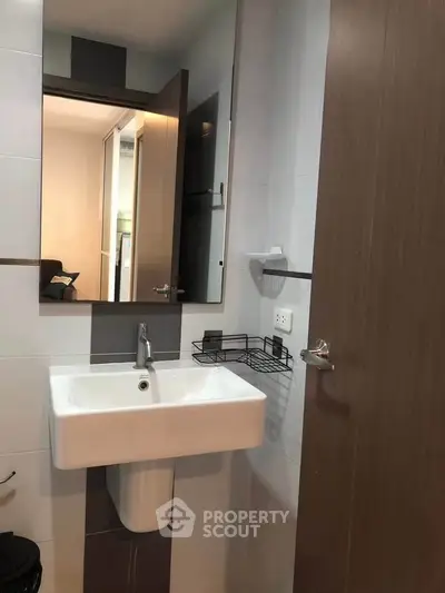Modern bathroom with sleek sink and mirror in contemporary apartment.