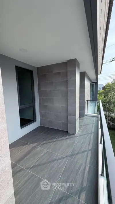 Spacious modern balcony with sleek tiles and glass railing, perfect for relaxation and enjoying outdoor views.