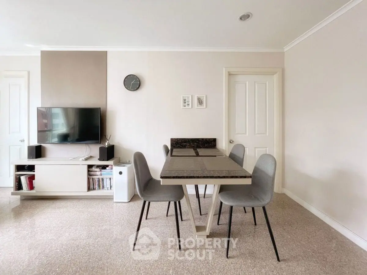 Modern dining area with sleek table and chairs, wall-mounted TV, and minimalist decor.