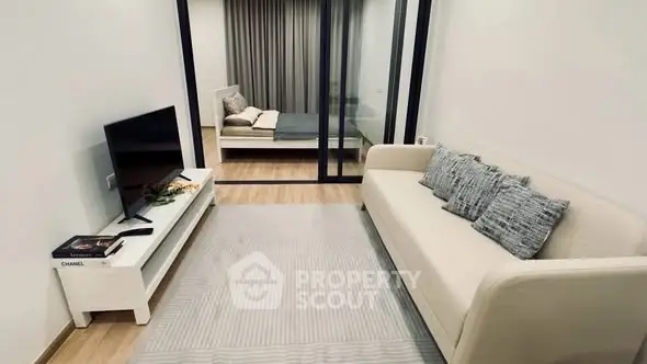 Modern living room with cozy sofa and TV, leading to a stylish bedroom.