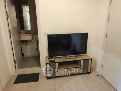Modern living room with sleek TV stand and adjacent bathroom, showcasing compact urban living.