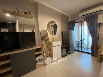 Modern living room with balcony access, featuring sleek furniture and a large TV, perfect for urban living.