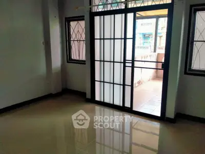 Spacious living room with large windows and sliding doors leading to a balcony, offering ample natural light.