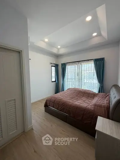 Spacious bedroom with elegant design and natural light, featuring a cozy bed and stylish curtains.